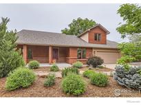 Charming single-story home with red brick accents, a covered front porch, and lush landscaping at 5420 Crestone Cir, Boulder, CO 80301