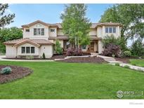 Stunning two-story home with a sprawling green lawn, mature trees, and a charming tiled roof at 7760 Crestview Ln, Niwot, CO 80504