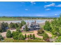 Stunning aerial view of a lakeside home with lush landscaping and a circular driveway at 7785 Darvey Ln, Longmont, CO 80504