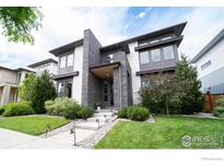 Modern home featuring a landscaped front yard and a stylish entrance with stone accents and walkway lights at 9415 E 58Th Dr, Denver, CO 80238