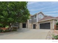 Charming two-story home with stone accents, gray siding, and a spacious driveway at 14075 Willow Wood Ct, Broomfield, CO 80020