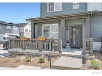 Inviting front porch of a modern townhome featuring stone landscaping, gray railings, and a welcoming entrance at 14553 W 91St Dr # A, Arvada, CO 80005