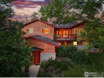Stunning two-story home with lush landscaping and a charming balcony against a beautiful sunset backdrop at 1484 Wicklow St, Boulder, CO 80303
