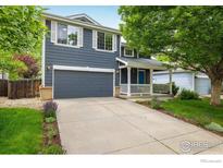 Charming two-story home featuring a manicured lawn, blue accents, and an attached two-car garage at 1672 Maccullen Dr, Erie, CO 80516