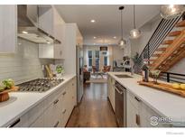 Modern kitchen featuring stainless steel appliances, white cabinetry, an open layout, and wood floors at 2139 N Downing St, Denver, CO 80205
