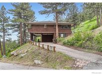 A charming two-story home featuring a sloped driveway and wood exterior at 27 Arrowleaf Ct, Boulder, CO 80304