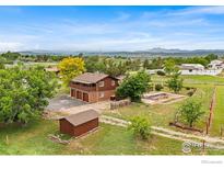 An exterior view of the house featuring a spacious yard, mature trees, and an in-ground pool at 2800 Lake Hollow Rd, Berthoud, CO 80513