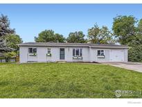 Charming home featuring a manicured front lawn and a classic, welcoming facade with flower-filled window boxes at 7442 Jay Ct, Arvada, CO 80003