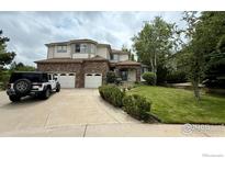 Charming two-story home featuring a brick facade, three-car garage, and well-manicured lawn at 7858 Oban Ct, Lone Tree, CO 80124