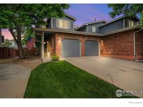 Charming two-story home with a brick facade, gray garage doors, and a well-manicured lawn at 12545 Elm St, Thornton, CO 80241