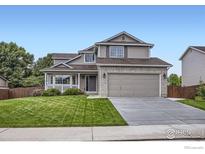 Charming two-story home features a brick-accented facade, attached two-car garage, a well-maintained lawn, and a welcoming front porch at 1641 Cedarwood Dr, Longmont, CO 80504