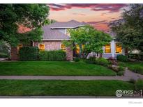 Charming brick home featuring lush landscaping and a welcoming front yard at sunset at 2133 Indian Peaks Cir, Longmont, CO 80504