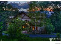 Charming two-story home featuring stone accents, warm lighting, and mountain views at sunset at 23 Hess Ave, Golden, CO 80401