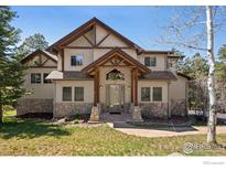 Charming two-story home featuring stone accents, wood trim, and a covered entryway, set amidst a lush lawn and mature trees at 23 Hess Ave, Golden, CO 80401