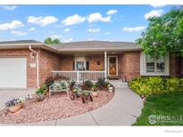 Charming single-story brick home with a cozy porch, lush landscaping, and a welcoming walkway at 233 Elizabeth Ct, Fort Lupton, CO 80621