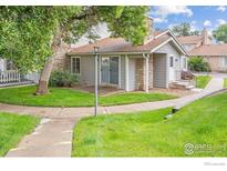 Charming townhome exterior with stone accents, well-maintained lawn, and inviting walkway at 8423 Everett Way # A, Arvada, CO 80005