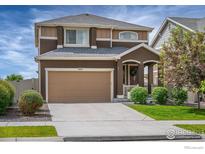 Charming two-story home featuring a well-manicured lawn, a two-car garage, and a welcoming covered front porch at 970 Auburn Dr, Erie, CO 80516