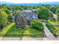 Charming two-story home featuring a well-manicured lawn, mature trees, and a welcoming white picket fence at 1005 Creek Ct, Longmont, CO 80503