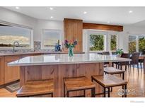 Bright kitchen showcasing a large island with seating, light wood cabinets, and scenic views from the windows at 1067 W Alder St, Louisville, CO 80027