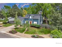 Charming two-story home with a blue exterior, lush lawn, and mature trees at 1304 Ceres Dr, Lafayette, CO 80026