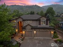 Charming two-story home boasts a stone facade, three-car garage, and lush landscaping against a mountain backdrop at 19061 Eagle Ridge Dr, Golden, CO 80401