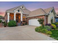 Charming brick home featuring a well-manicured lawn and inviting front porch with beautiful landscaping at 2324 Steppe Dr, Longmont, CO 80504