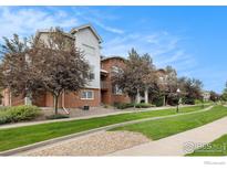 Brick townhomes with trees and lawn under a blue sky on a sunny day at 85 Uinta Way # 605, Denver, CO 80230