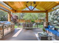Inviting backyard patio featuring a built-in grill, dining table, and comfortable seating area with a beautiful wood ceiling at 1069 Monarch Way, Superior, CO 80027