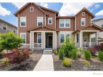 Charming townhome with brown siding, a welcoming front porch, and well-maintained landscaping at 1125 Anker Dr, Erie, CO 80516