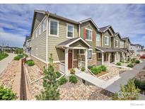 Inviting townhome featuring charming front porch, manicured landscaping, and neutral exterior color scheme at 16818 E 119Th Ave # A, Commerce City, CO 80022