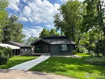 Charming home with lush green lawn, mature trees, and concrete walkway at 7800 Hygiene Rd, Longmont, CO 80503