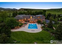 Stunning aerial view of luxury home with pool, lush landscaping, and mountain views at 8000 N 41St St, Longmont, CO 80503