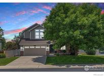Charming two-story home featuring a well-maintained front yard and mature tree at 10400 Foxfire St, Firestone, CO 80504