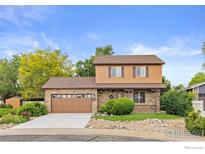 Charming two-story home featuring a stone facade, complemented by a well-manicured lawn and mature trees at 112 Melody Ln, Platteville, CO 80651