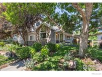 Charming home with lush landscaping, mature trees, and a welcoming stone facade at 1892 Bell Dr, Erie, CO 80516