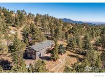 Stunning aerial view of mountain home with surrounding forest and distant mountain range at 223 Copperdale Ln, Golden, CO 80403