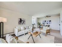Bright living room featuring a white sofa, light rug, and adjacent dining area, creating an inviting space at 850 20Th St # 704, Boulder, CO 80302