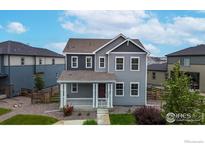 Charming two-story home showcasing a covered front porch, tidy landscaping, and complementary exterior colors at 10604 Reunion Pkwy, Commerce City, CO 80022