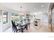 Bright dining area features mountain views, wood table, and a stylish chandelier adjacent to the modern kitchen at 10886 Pheasant Run, Littleton, CO 80125