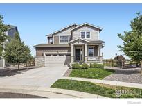 Two-story home featuring a stone-accented front, a covered porch, manicured lawn, and attached two-car garage at 12889 Clearview St, Firestone, CO 80504