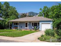 Charming single-story home featuring a covered front porch and a well-maintained lawn with mountain views in the background at 309 27Th St, Boulder, CO 80305