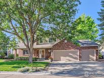 Two-story home with brick and siding, attached three-car garage, mature trees, and manicured front lawn at 3124 Marlin Dr, Longmont, CO 80503