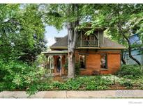 Charming red-brick home featuring a turret, covered porch, and lush landscaping at 446 Pearl St, Boulder, CO 80302