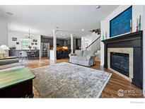 Spacious living room with hardwood floors, fireplace and open access to the kitchen and dining area at 4915 Sage Brush Dr, Broomfield, CO 80023