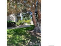 Landscaped front yard with mature trees, lush green lawn, and a sidewalk leading to the home's entrance at 4985 Twin Lakes Rd # 94, Boulder, CO 80301