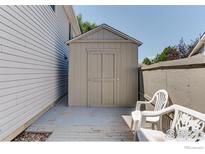 Neutral backyard shed sitting on a concrete pad near a fence and some patio chairs at 647 Florence Ave, Firestone, CO 80520