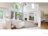 Bright living room with large windows, fireplace, and vaulted ceilings at 7597 Bison Ct, Littleton, CO 80125