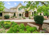 Charming home showcasing a stone facade, arched entry, lush landscaping, and a beautifully paved walkway at 8911 Little Raven Trl, Niwot, CO 80503