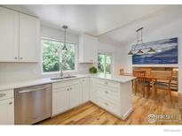 Bright kitchen features white cabinets, stainless steel appliances and a window view to the trees at 137 S Polk Ave, Louisville, CO 80027