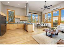 Bright open-concept living room boasts hardwood floors, large windows, and modern kitchen with stainless appliances at 1455 Yarmouth Ave # 211, Boulder, CO 80304